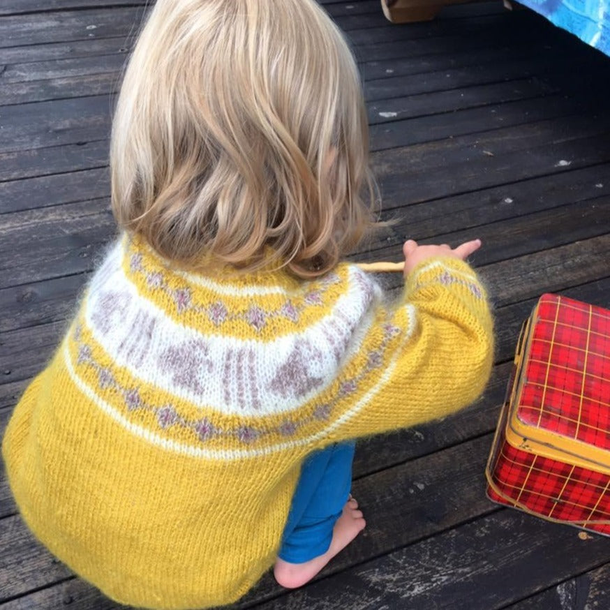 Child playing wearing wool knitted jumper yellow